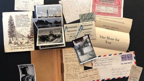 A collage of vintage postcards, photographs, letters, and tickets on a dark surface.