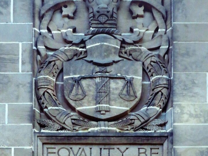 Stone relief with justice scales and text "Equality Before the Law."