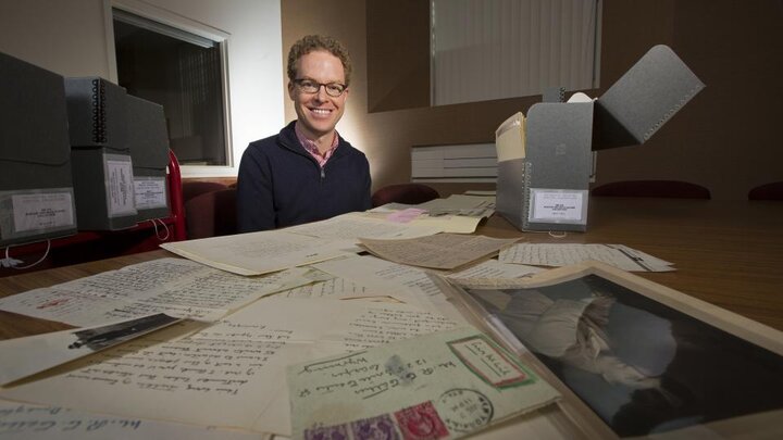 Photo of Andrew Jewell sitting at a table covered with letters by Willa Cather.